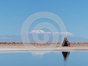 Hut reflected on blue lake with snow mountains in the back