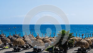 Hut umbrellas on the beach, sea on background, Tenerife