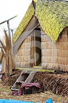 A hut with a yellow roof made of reeds by the native indians that is standing in a man made island at Lake Titicaca in Peru, South