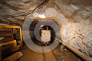 Hutch cart with raw material standing at underground mining. Production and technology concept. Tunnel with railway and