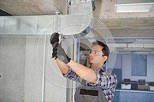 hvac indian worker install ducted pipe system for ventilation and air conditioning. copy space