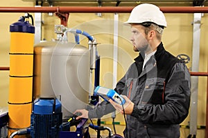 HVAC maintenance engineer checking technical data of heating system equipment in boiler room