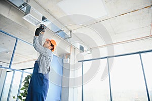hvac services - indian worker install ducted pipe system for ventilation and air conditioning in house