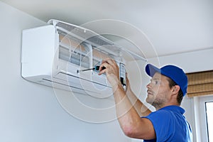 hvac services - technician installing air conditioner on the wall photo