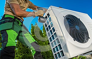 HVAC Technician Installing Large Modern Heat Pump