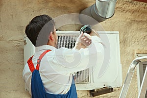 HVAC technician working on a capacitor part for condensing unit