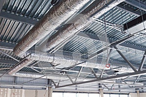 HVAC. Ventilation pipes in silver insulation material hanging from the ceiling inside new building.