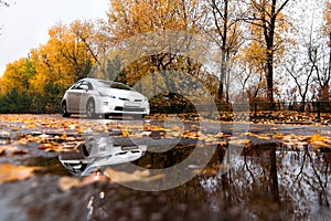 Hybrid car on autumn road in rainy day