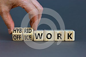 Hybrid or office work symbol. Businessman turns cubes and changes words `office work` to `hybrid work`. Beautiful grey backgro