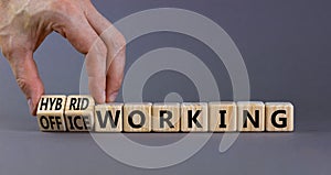 Hybrid or office working symbol. Businessman turns cubes and changes words `office working` to `hybrid working`. Beautiful gre