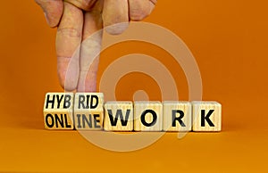 Hybrid or online work symbol. Businessman turns cubes and changes words `online work` to `hybrid work`. Beautiful orange