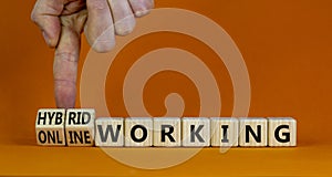 Hybrid or online working symbol. Businessman turns cubes and changes words `online working` to `hybrid working`. Beautiful ora