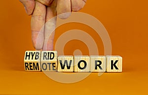 Hybrid or remote work symbol. Businessman turns cubes and changes words `remote work` to `hybrid work`. Beautiful orange