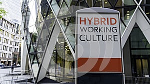 Hybrid Working Culture on a city-center sign in front of a modern office building photo