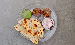 Hydrabadi Kabab Paratha with green chili sauce & Onion on transparent plate. photo