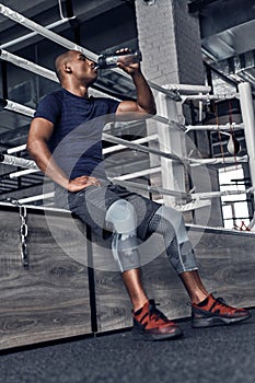 Hydrating. Handsome young African man in sport clothing drinking