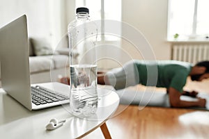 Hydration is important. Close up shot of water bottle, laptop and wireless earbuds on the table. Young active man
