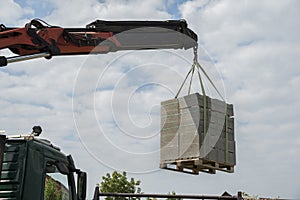 Hydraulic arm is unloading concrete block for a house