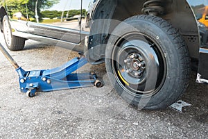 Hydraulic car jack lift car to replace punctured tyre with temporary emergency replacement tyre