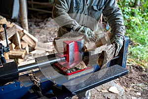 Hydraulic log splitter blade cuts into wood with workman and woodpile