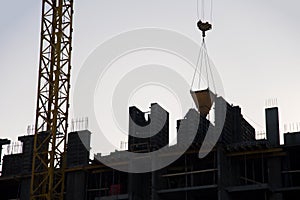 Hydraulic luffing jib tower crane and workers being poured concrete into foundation. Cement pouring into formwork of building at