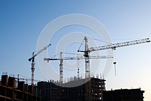 Hydraulic luffing jib tower cranes and workers being poured concrete into foundation.