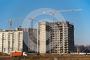 Hydraulic luffing jib tower cranes and workers being poured concrete into foundation. Cement pouring into formwork of building at