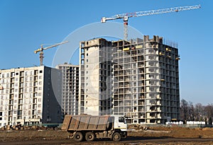 Hydraulic luffing jib tower cranes and workers being poured concrete into foundation. Cement pouring into formwork of building at