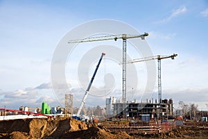 Hydraulic luffing jib tower cranes and workers being poured concrete into foundation. Cement pouring into formwork of building at