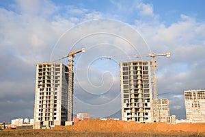 Hydraulic luffing jib tower cranes and workers being poured concrete into foundation. Cement pouring into formwork of building at