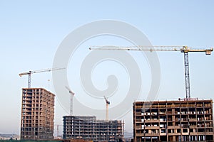 Hydraulic luffing jib tower cranes and workers being poured concrete into foundation. Cement pouring into formwork of building at