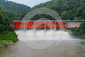 Hydro dam structure with open gates releasing muddy flood water