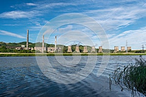 Hydro-electric station on the river bank and blue sky with clouds