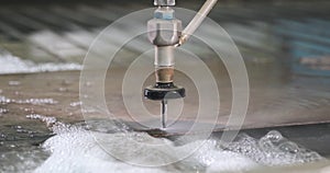 Hydroabrasive high pressure CNC machine is cutting out a shape on a metal sheet.