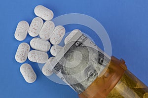 Hydrocodone tablets with Benjamin Franklin on a hundred dollar bill and a pill bottle.