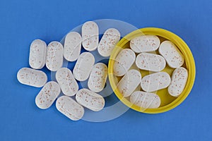 Hydrocodone tablets in a yellow cap against a blue background. Opiate addiction costs the U.S. economy $78.5 billion per year