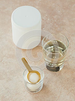 Hydrolyzed marine sourced collagen peptides in glass bowl and water on a light beige background. Daily supplement concept
