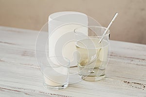 Hydrolyzed marine sourced collagen peptides in glass bowl and water on a white wooden background