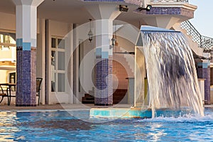 Hydromassage water with gentle splashes at spa resort. Waterfall flow in spa swimming pool. Hydrotherapy, health and