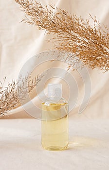 Hydrophilic cleanser oil on linen drapery and dry plant. Makeup remover cosmetic beauty skincare product mockup. Concept