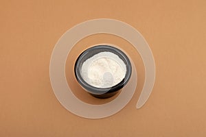 Hydroxybutanedioic acid or malic acid in black ceramic bowl. White powder with Chemical formula C4H6O5. Food additive E296, photo