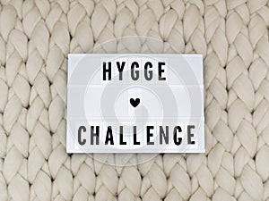 HYGGE CHALLENGE word on lightbox on knit background. Cozy compozition. Knit background.