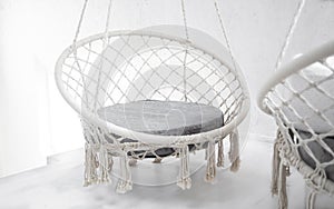 Hygge scene with white hammock chair with grey pillow on white background. Cozy home interior