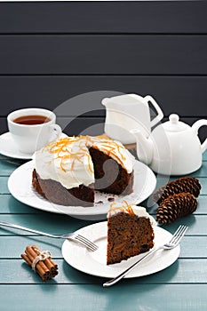 Hygge tea party. Black tea and traditional fruit cake with cream icing and orange peel on blue background
