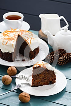 Hygge tea time. Black tea and homemade fruit cake with cream icing and orange peel on blue background