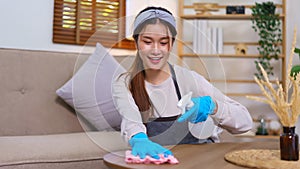 Hygiene cleaning concept, Housemaid using cloth and spray to wipe the dust on table in living room