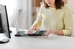 Close up of woman cleaning keyboard with sanitizer photo