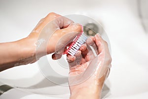 Hygiene. Close-up view of a young girl washing her hands with soap and a brush. A woman washes her hands in the sink to get rid of
