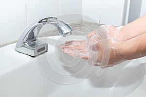 Hygiene concept cleaning hand and washing hands. A man washes his hands with soap in the basin