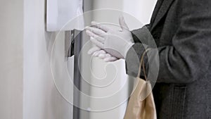 Hygiene and Healthcare. Hands in gloves using automatic touch less sanitizing dispenser with antiseptic during COVID-19